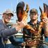 Two fisherman holding a large lobster
